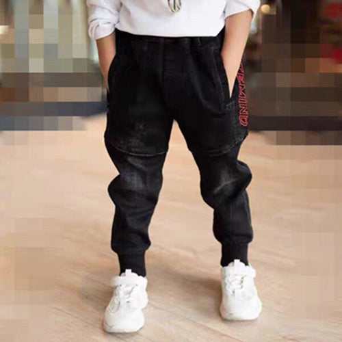 Person wearing black pants with red text and white sneakers on a blurred background