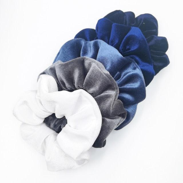 Set of four scrunchies in blue, gray, and white on a white background