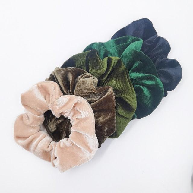 Set of five velvet scrunchies in various colors on a white background