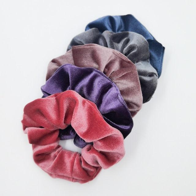 Set of five velvet scrunchies in various colors on a white background