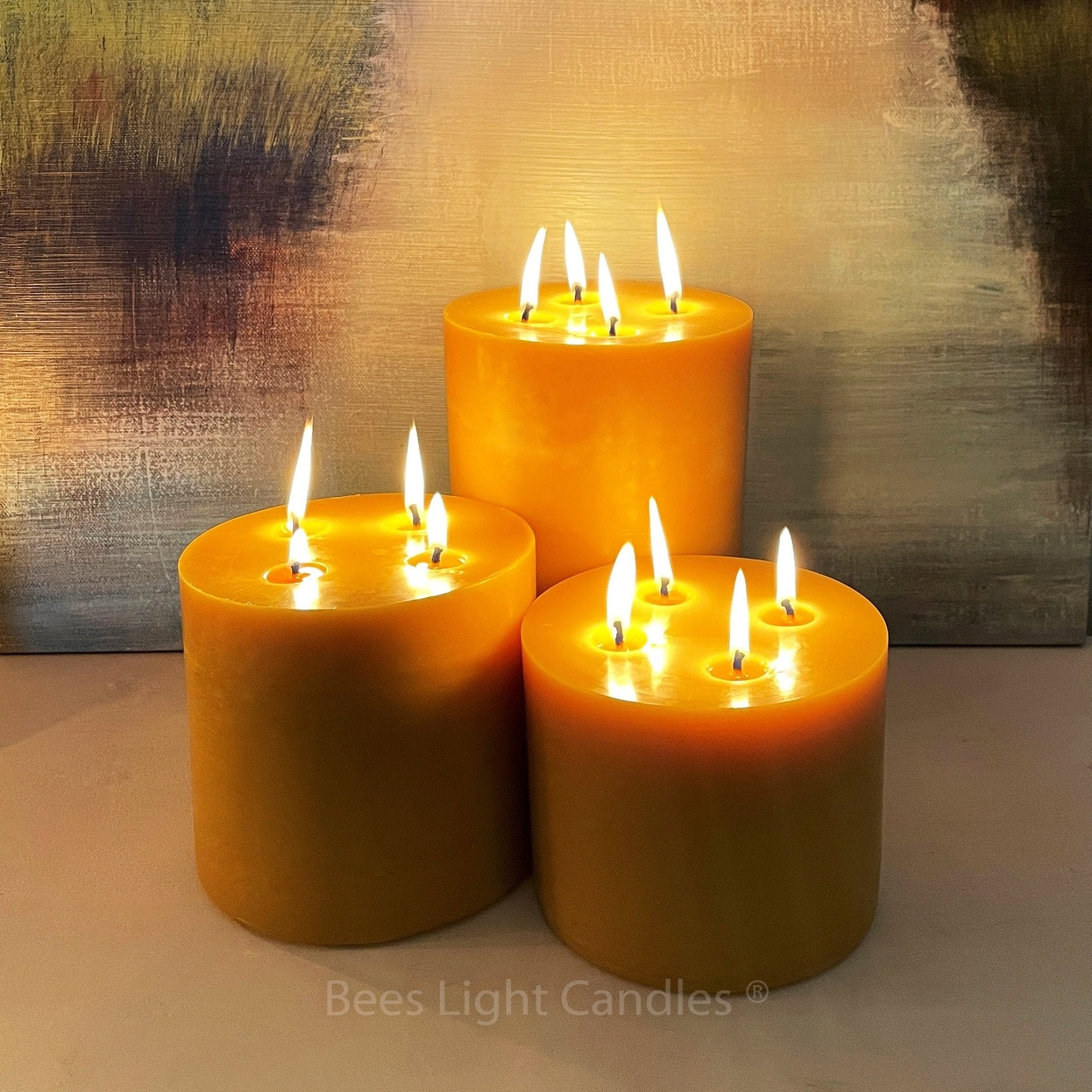 Three lit candles on a textured surface with 'Bees Light Candles' branding.
