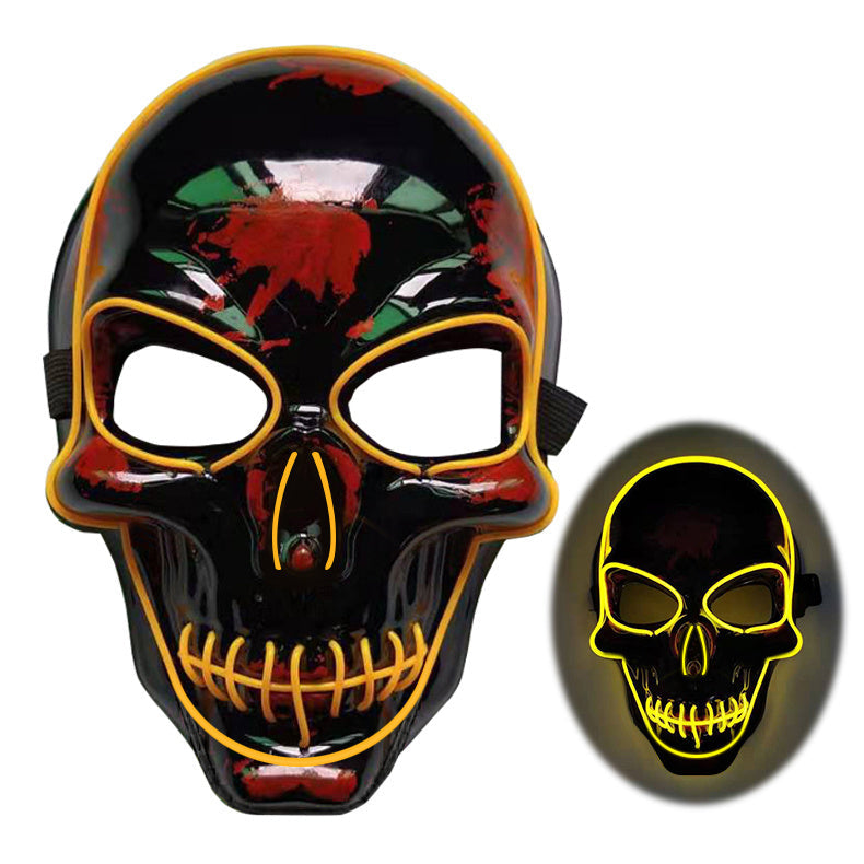 Black skull mask with yellow accents and a close-up inset on a white background
