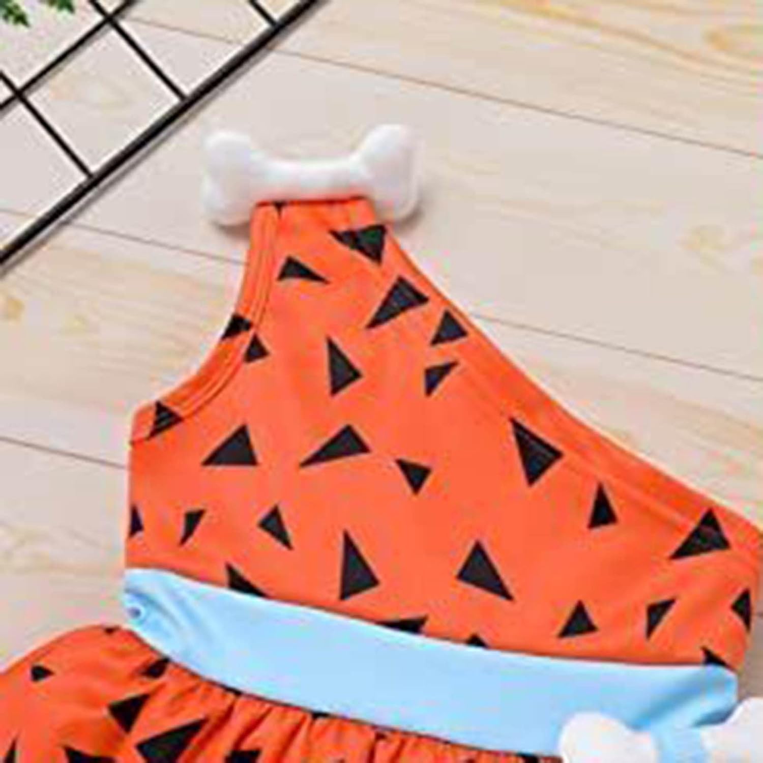 Orange dress with black triangle pattern on a wooden floor