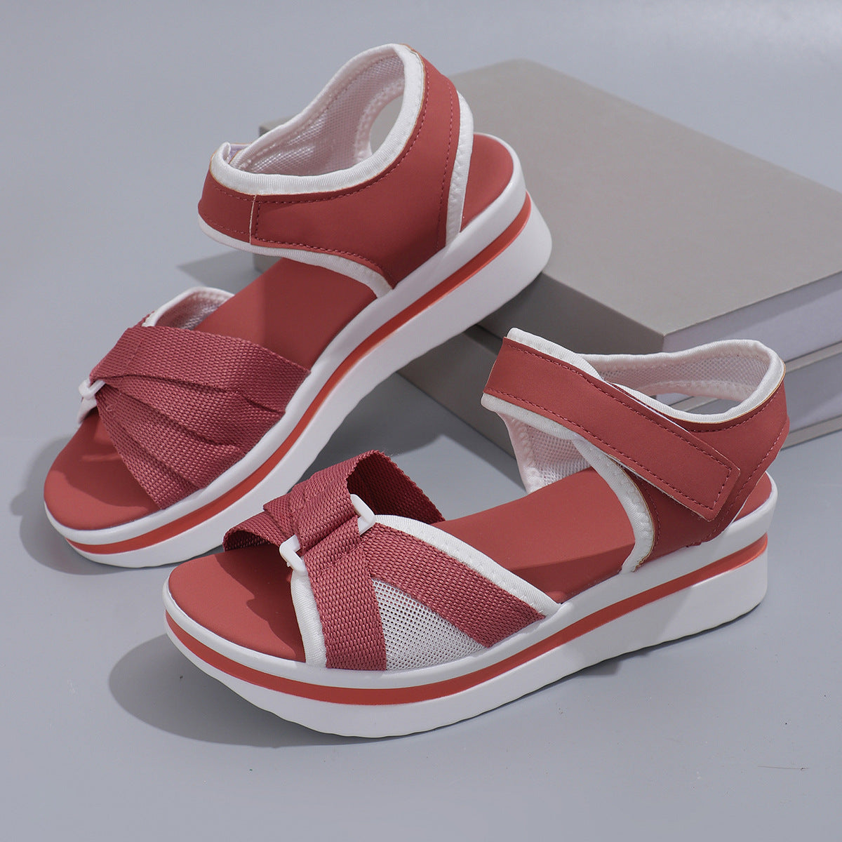 Red sandals with white straps on a gray background