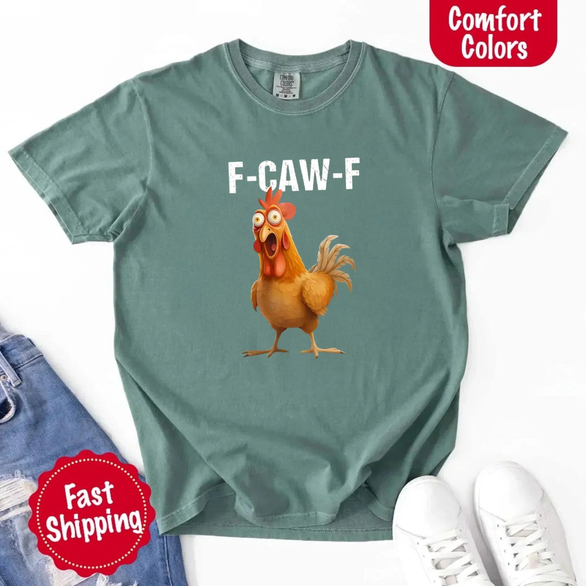 Green t-shirt with a cartoon chicken and 'F-CAW-F' text, displayed with jeans and sneakers on a white background.