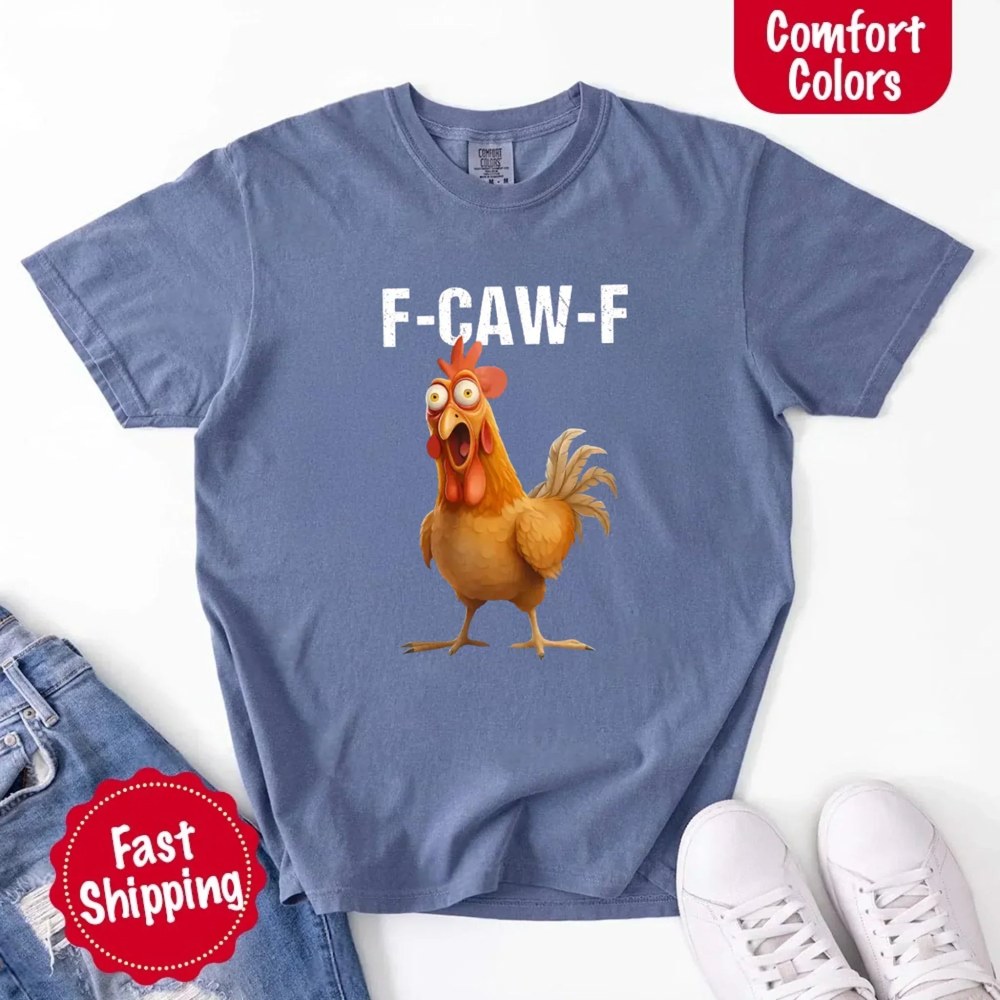 Blue t-shirt with a cartoon chicken and 'F-CAW-F' text, displayed with jeans and sneakers on a white background.