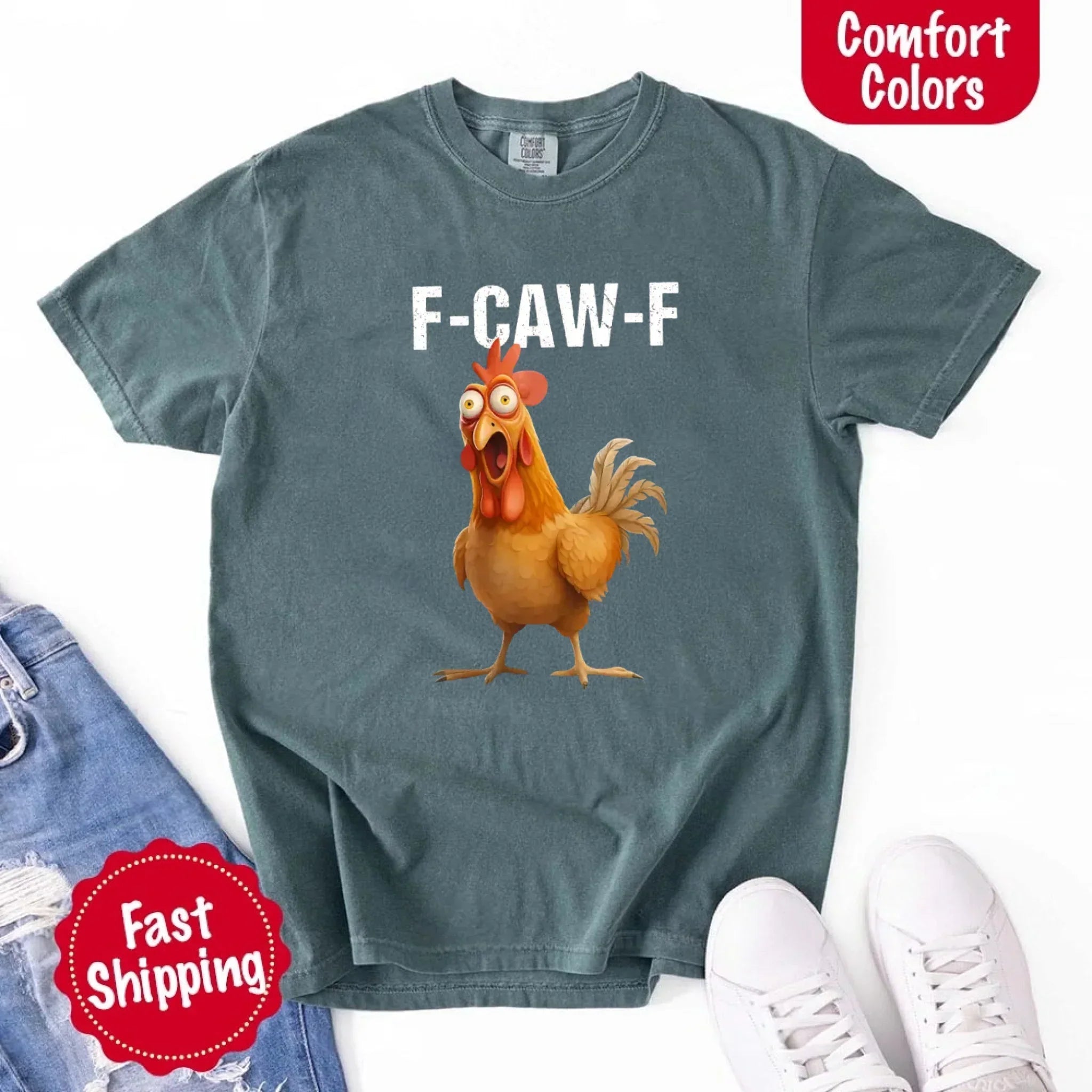 Teal t-shirt with a cartoon rooster and 'F-CAW-F' text, displayed with jeans and sneakers on a white background.