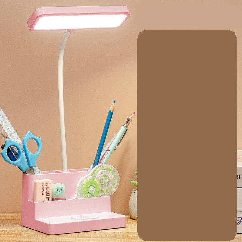 Pink desk lamp with stationery items on a wooden surface against a beige background