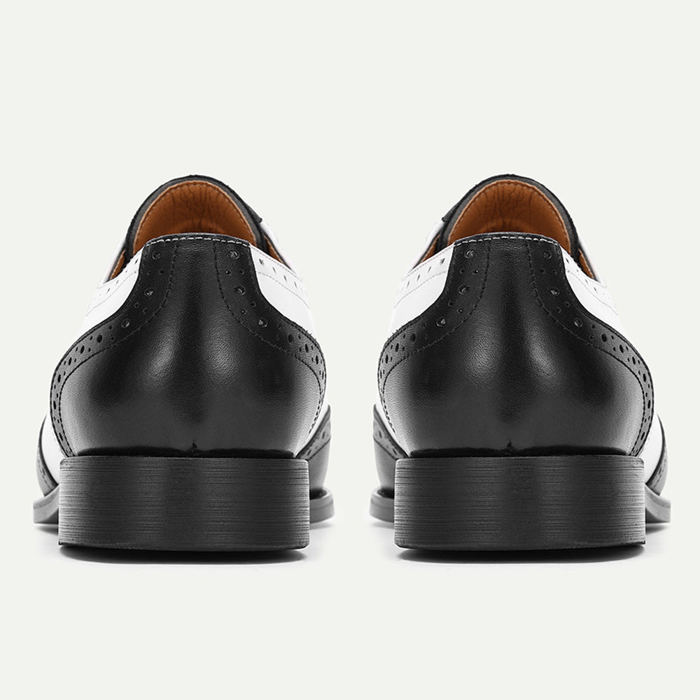 Black leather dress shoes with white accents on a light gray background