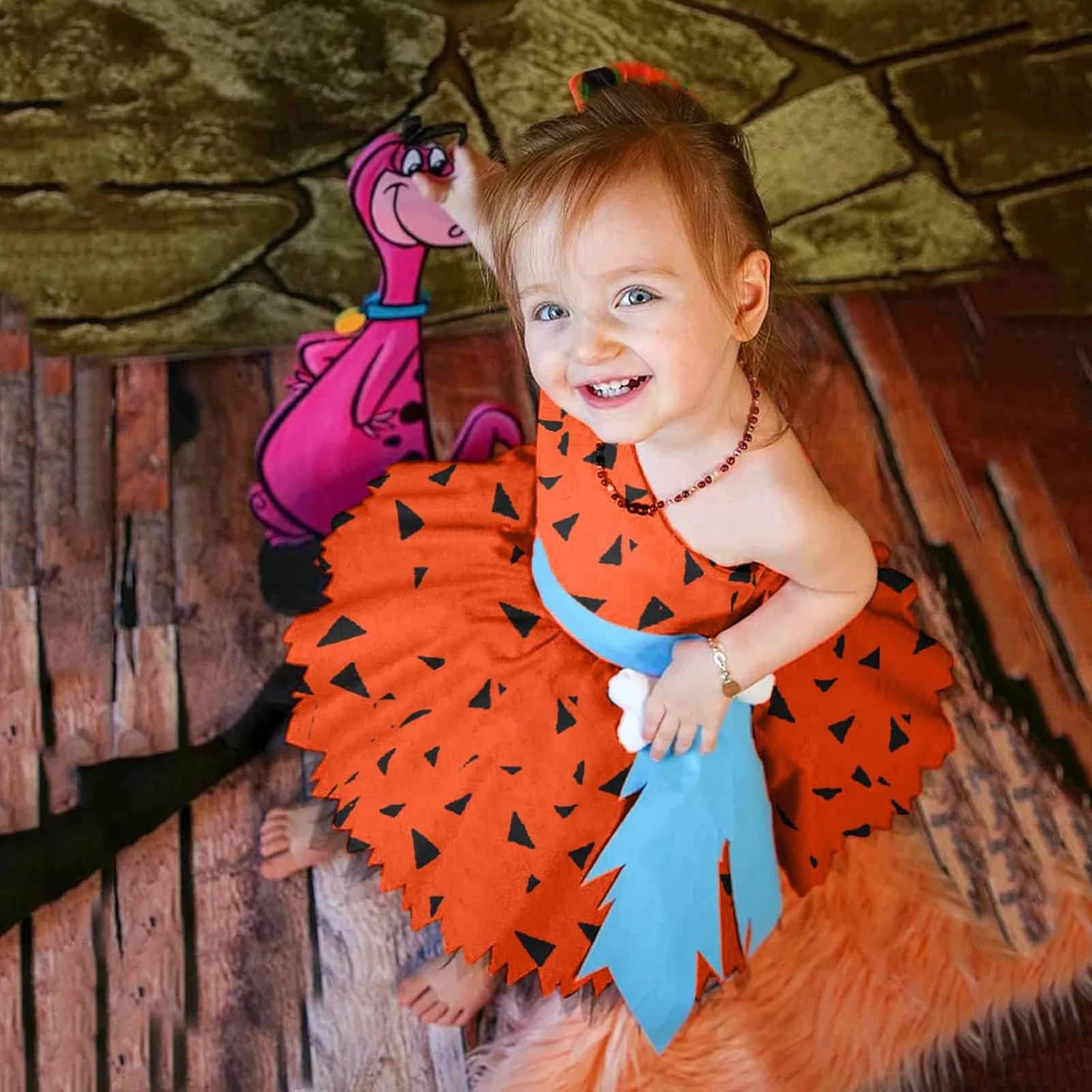 Child in a Flintstones costume with a pink character in the background