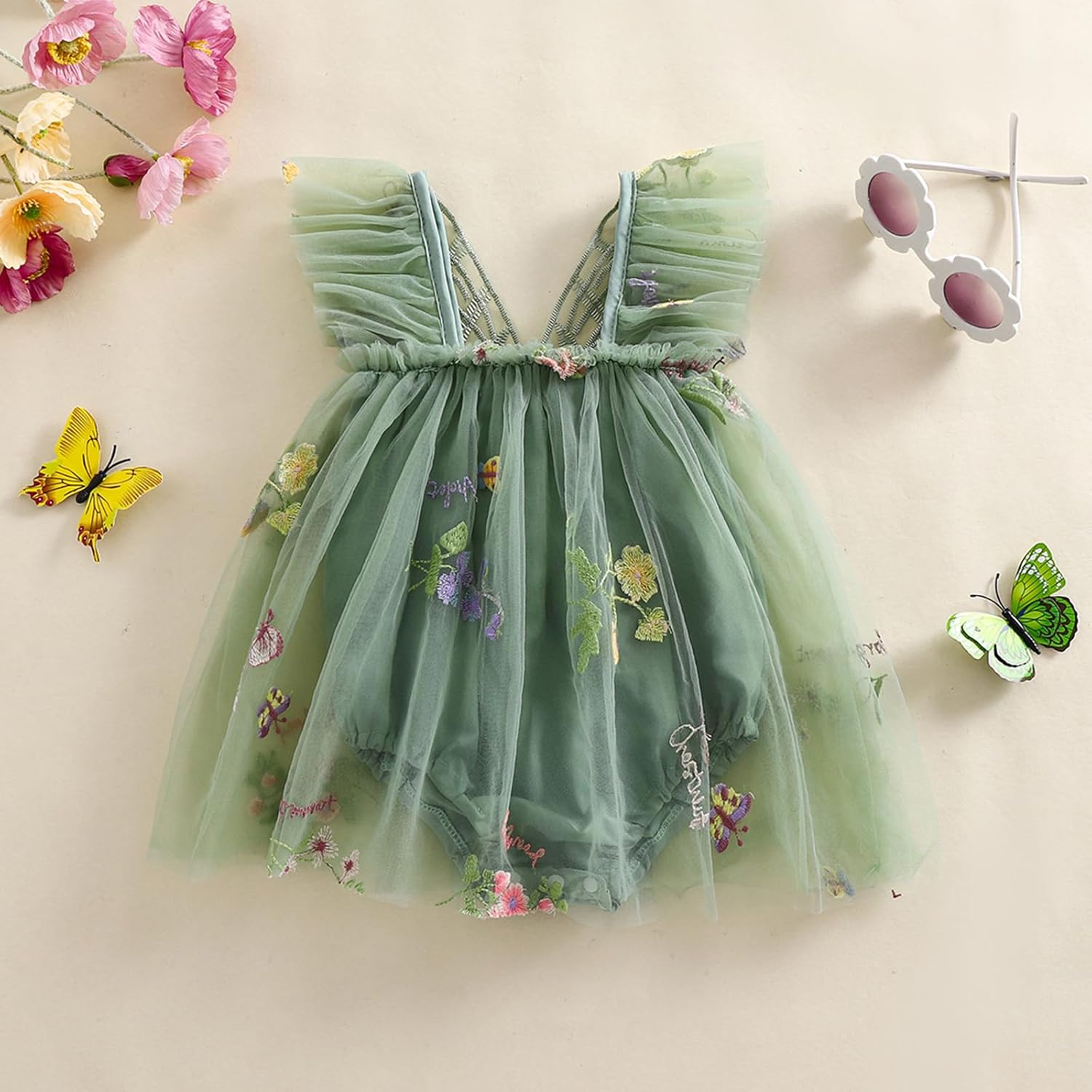 Green tulle dress with butterfly embellishments on a light background