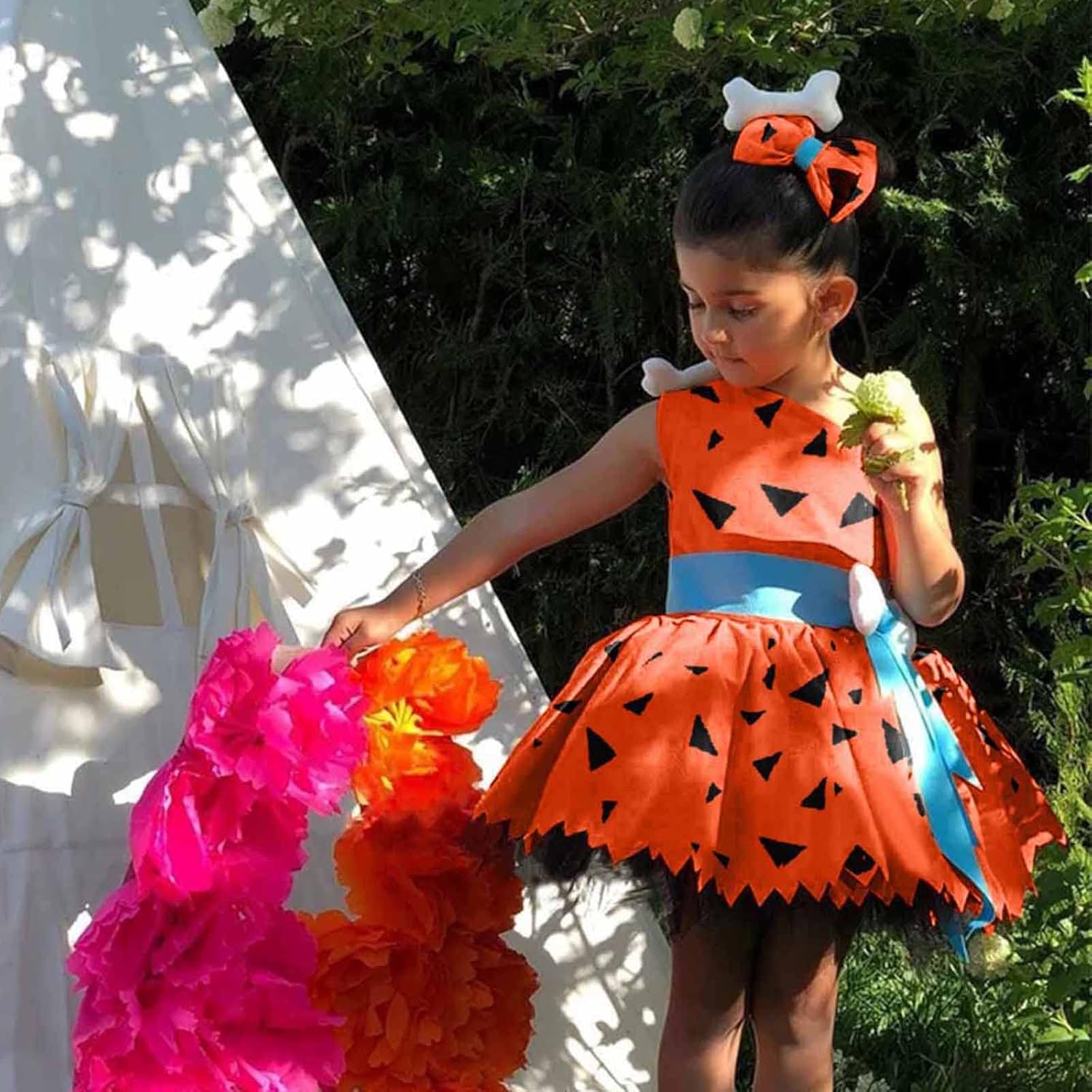 Child in a Halloween costume with orange and black dress, standing outdoors.