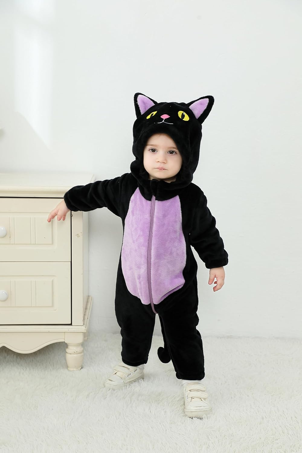 Child wearing a black cat costume with pink belly on a white background