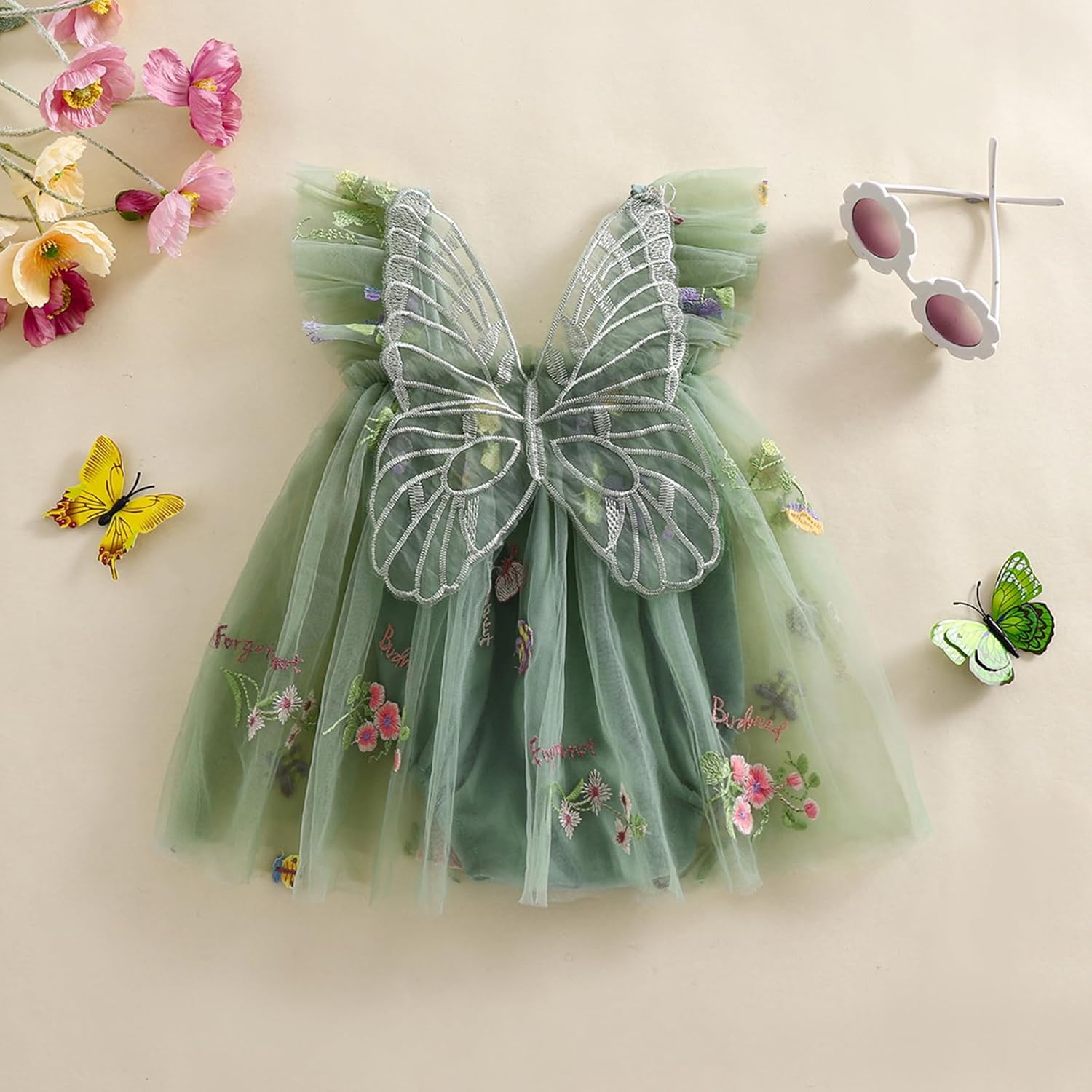 Green dress with butterfly wings and floral details on a beige background