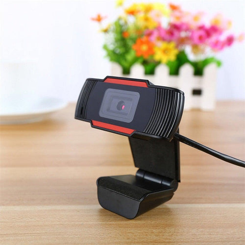 Webcam on a wooden surface with flowers in the background