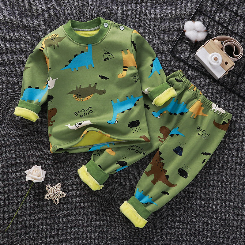 Children's green pajama set with dinosaur pattern on a dark textured surface.