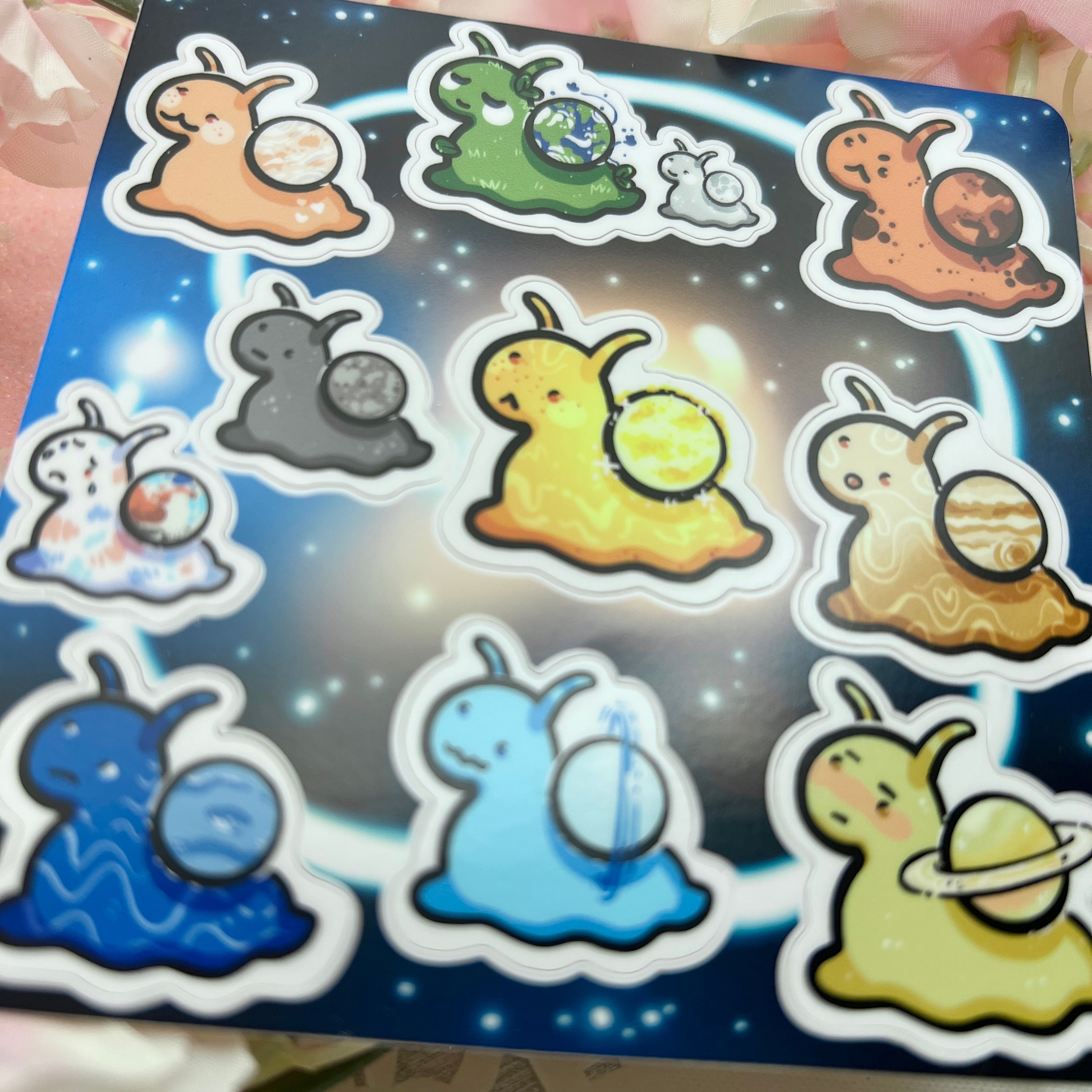 Sticker sheet featuring cute cartoon slugs each carrying a different planet on a galaxy background — solar system slug stickers