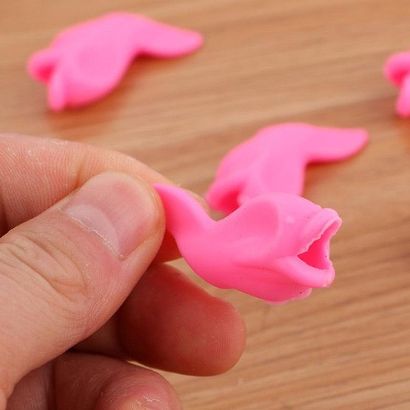 Pink silicone crab toy held by a hand on a wooden surface