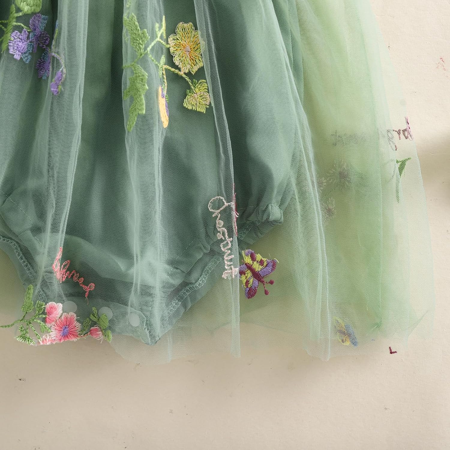 Green embroidered garment with floral designs on a light background