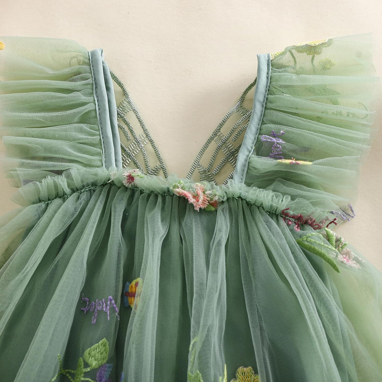 Green dress with floral embroidery on a beige background