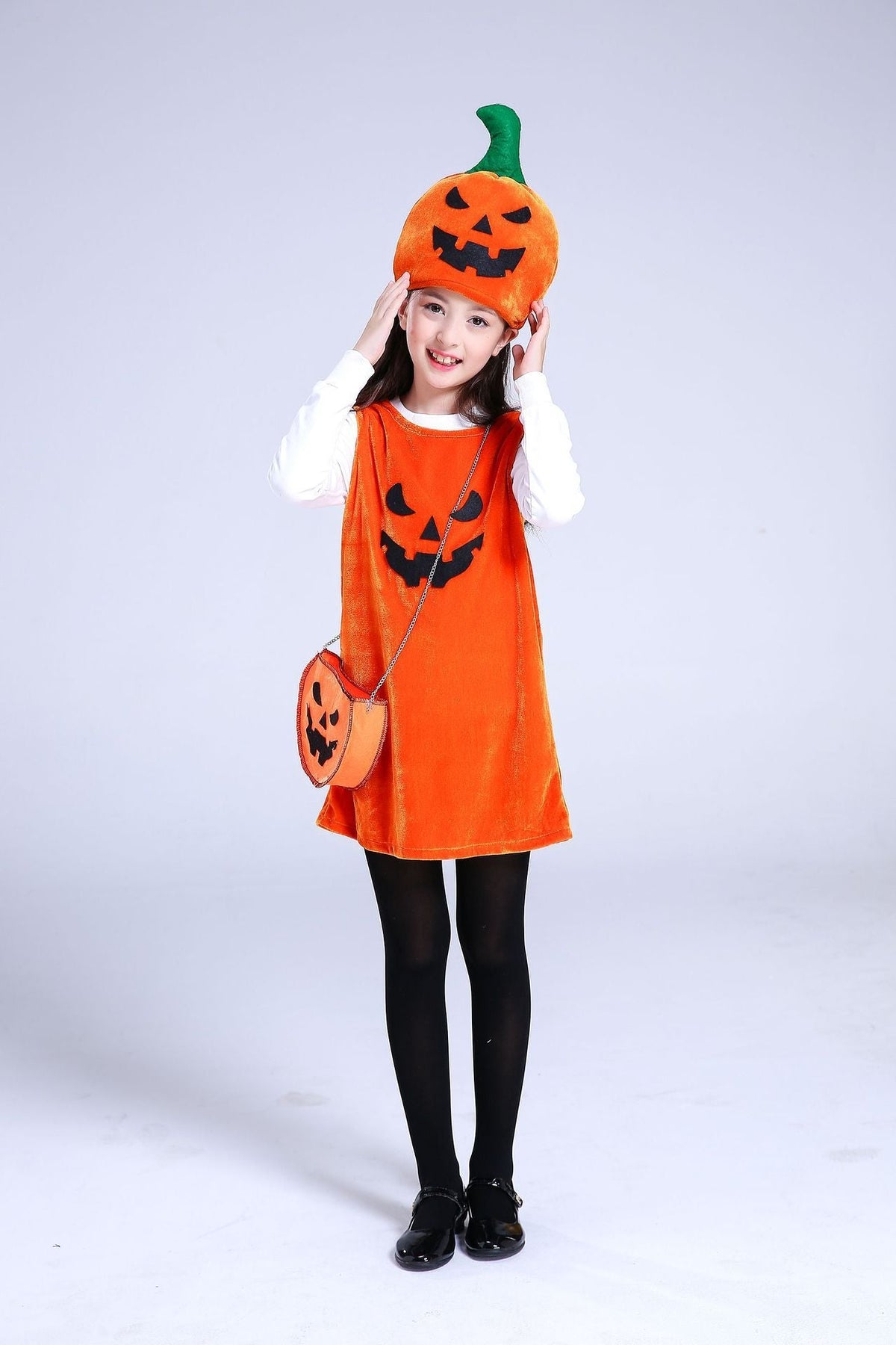 Child wearing an orange Halloween dress with a pumpkin design on a white background