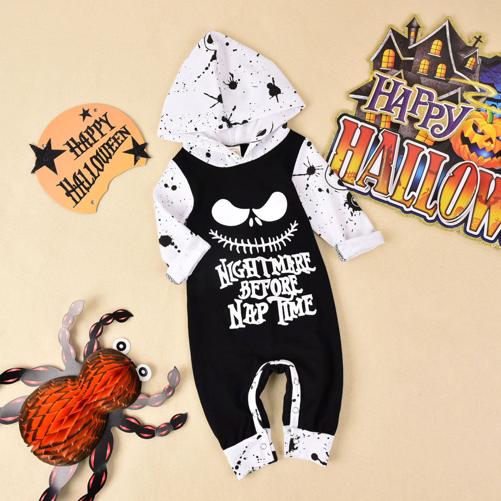 Halloween-themed baby romper with skull design and text, surrounded by Halloween decorations on a beige background.