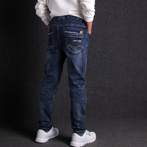Person wearing blue jeans with a visible brand logo on a dark background