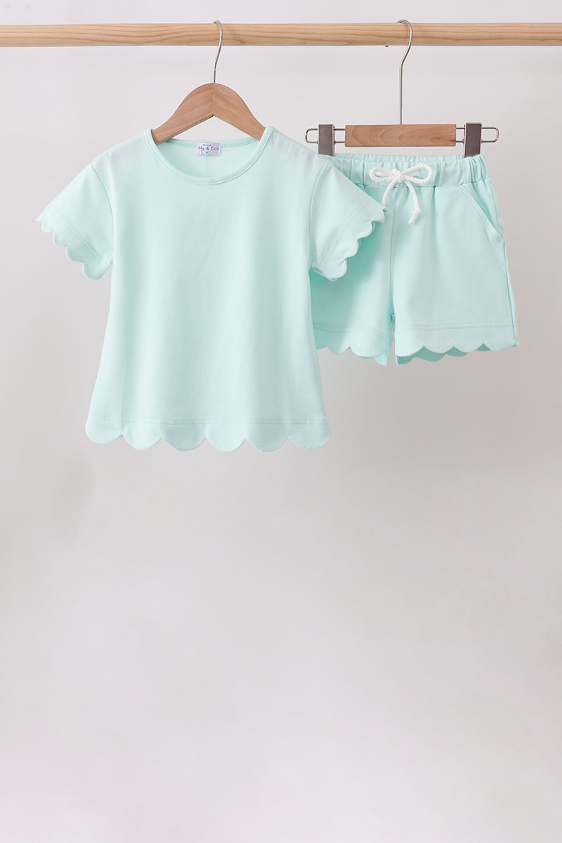 Light blue pajama set with ruffled shorts on a wooden hanger against a light background