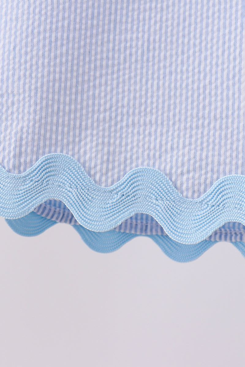 Close-up of a blue and white checkered fabric with wavy edge design.