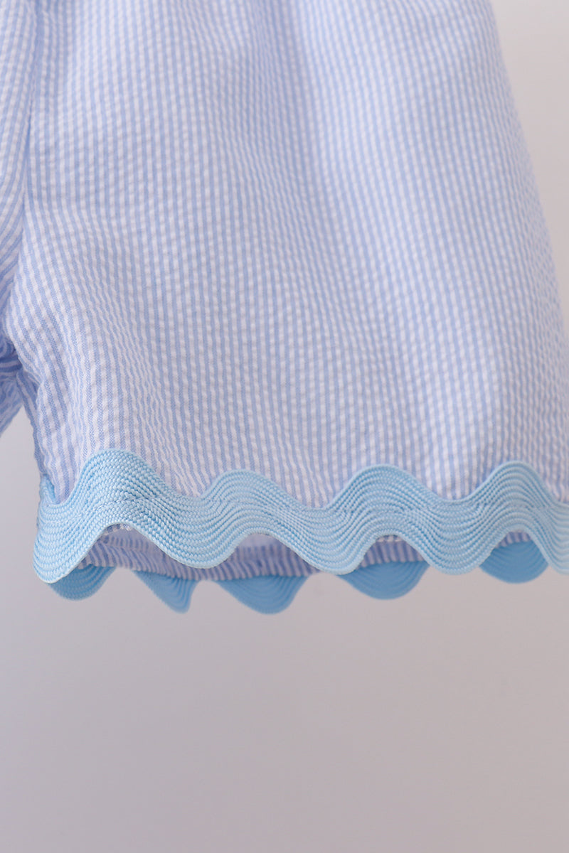 Close-up of a blue textured fabric with wavy edge on a light gray background