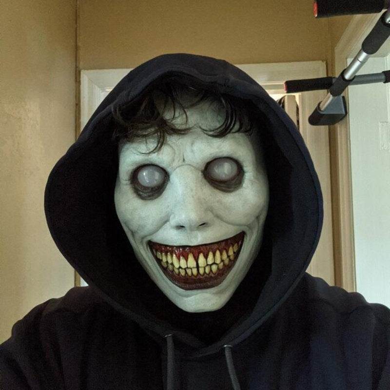 Person wearing a dark hoodie and a恐怖面具 with large eyes and a wide grin.