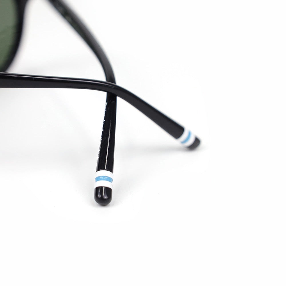 Close-up of a black eyeglass frame with a white and blue strip on a white background