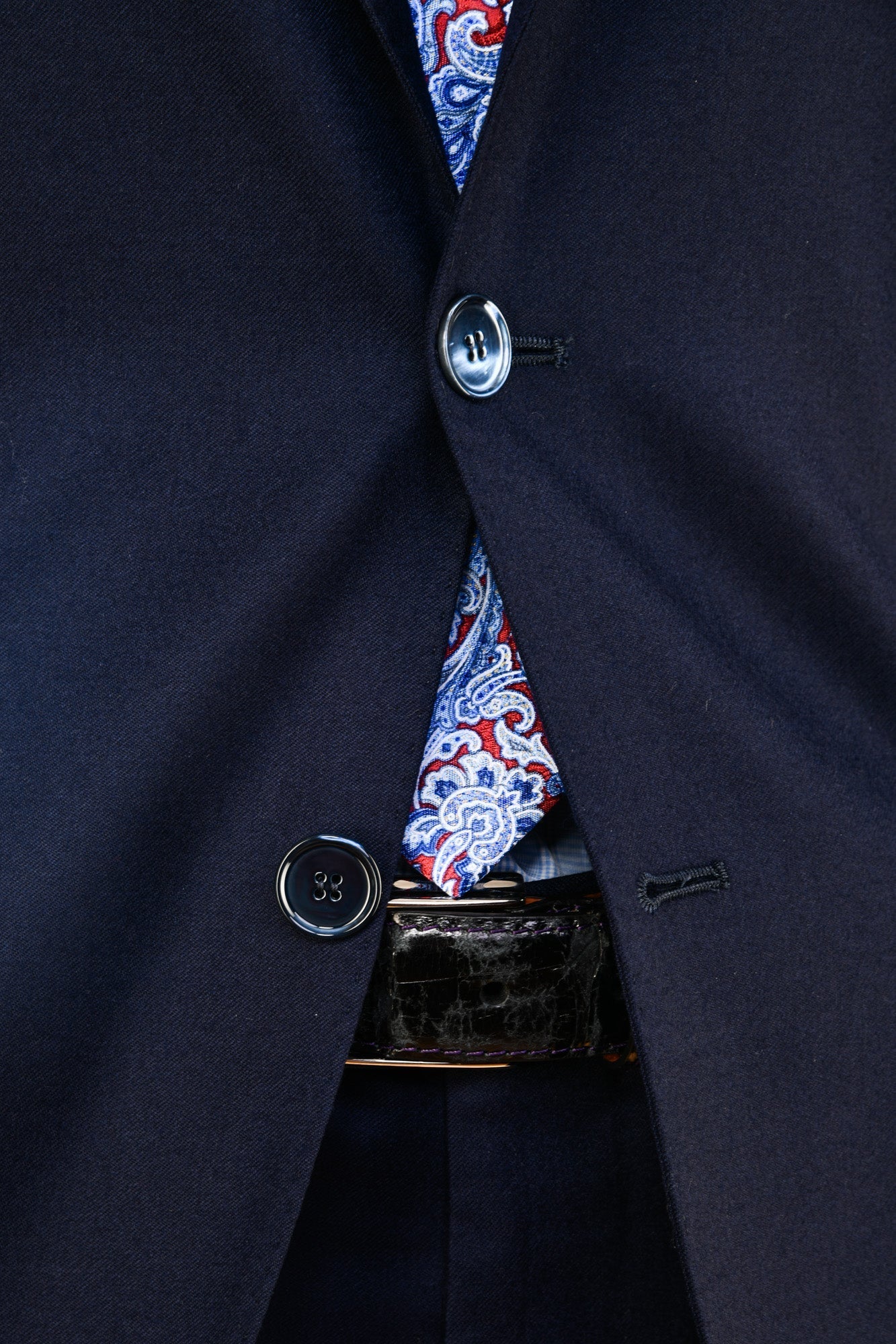 Navy suit jacket with a patterned shirt and belt buckle.