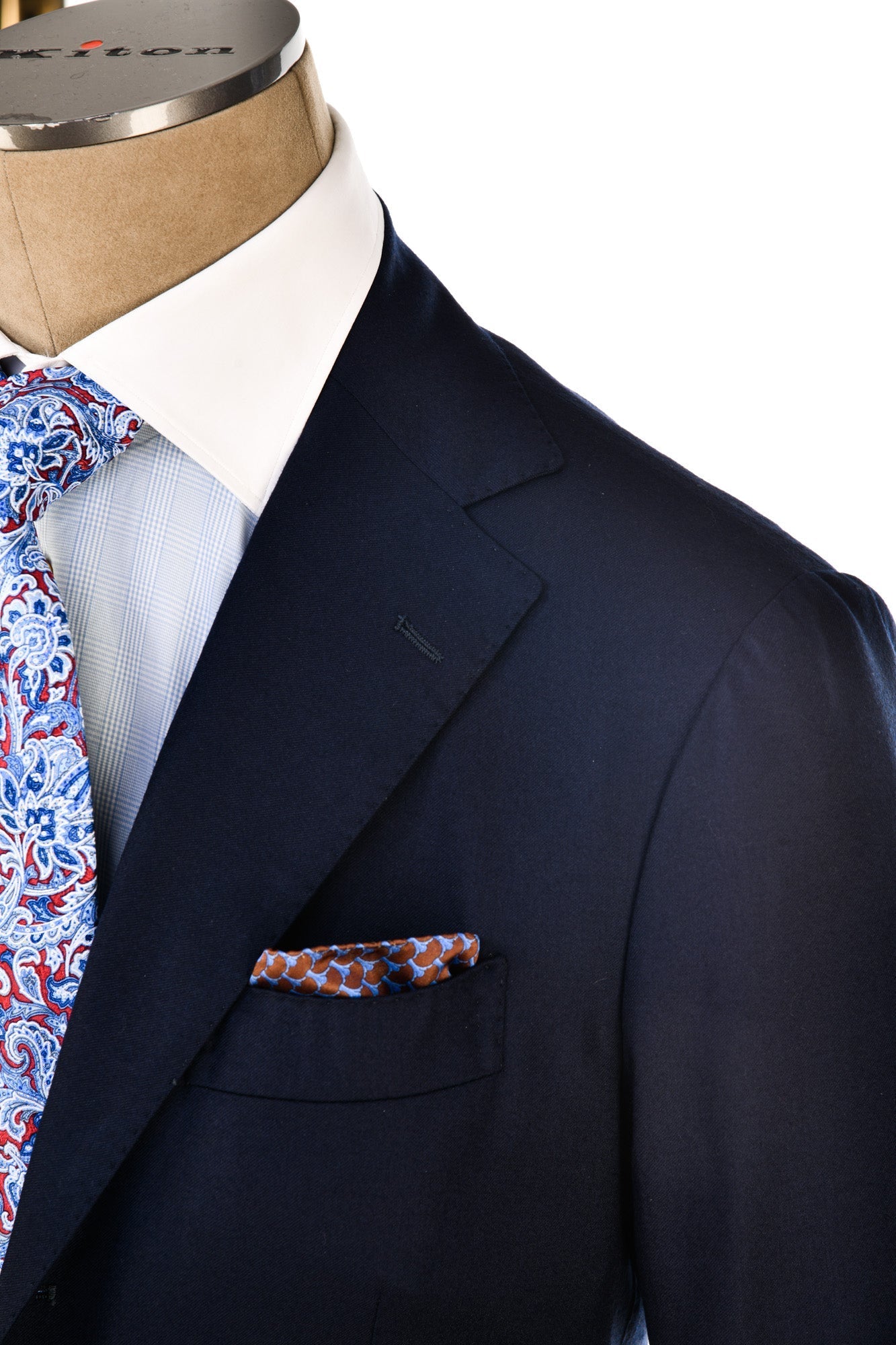 Navy suit jacket with a patterned tie and pocket square on a mannequin against a white background