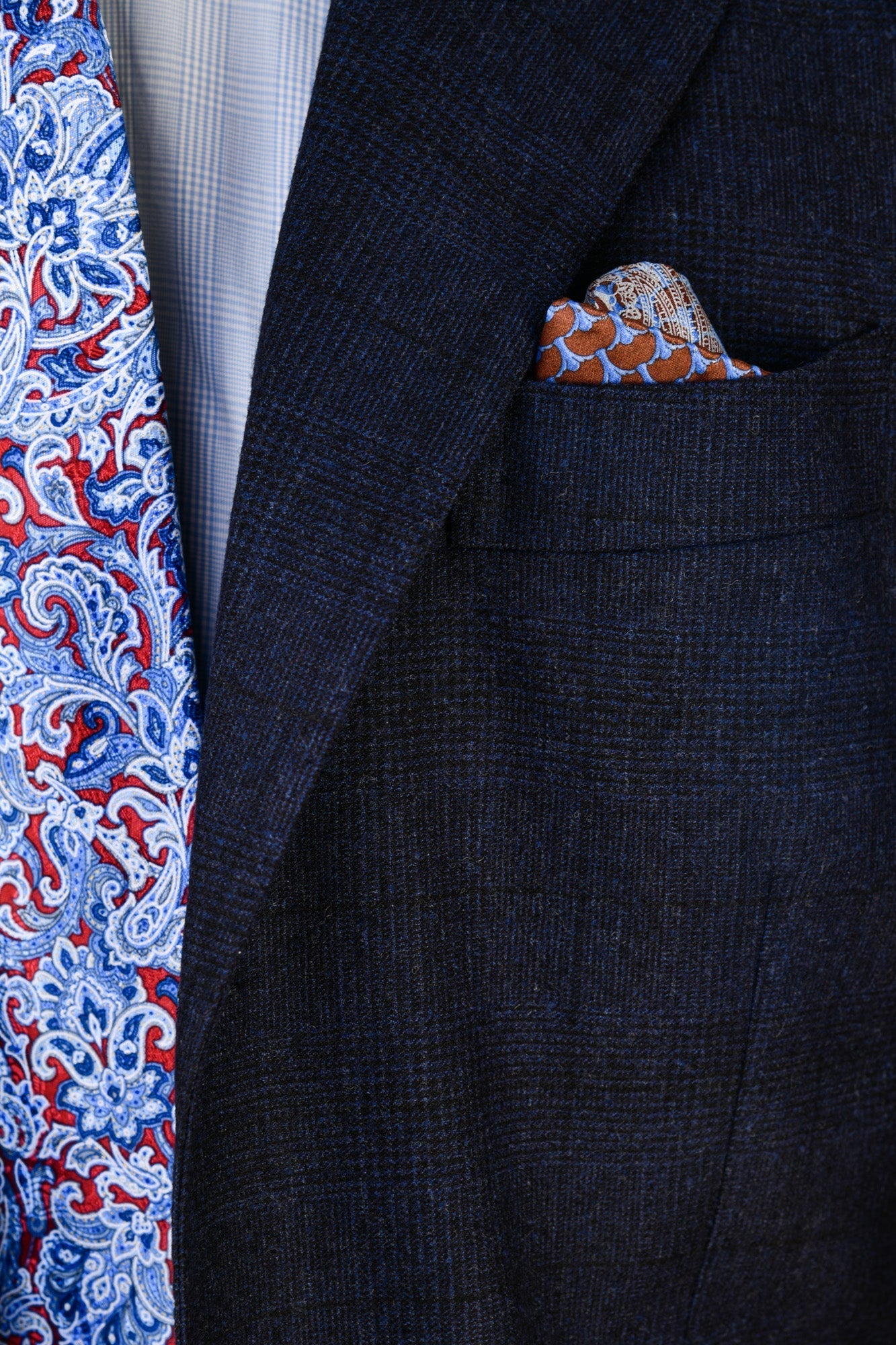 Navy suit jacket with a patterned pocket square and tie