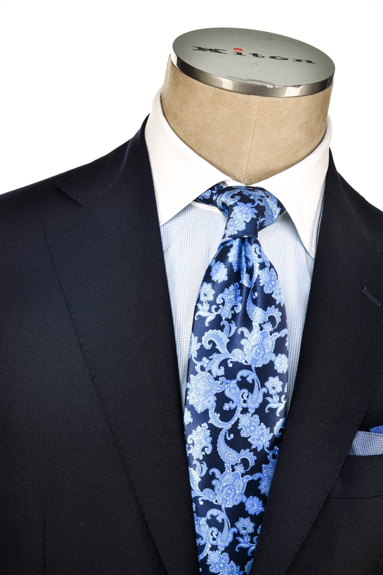 Mannequin wearing a dark suit with a white shirt and blue floral tie, branded 'Ritz'.