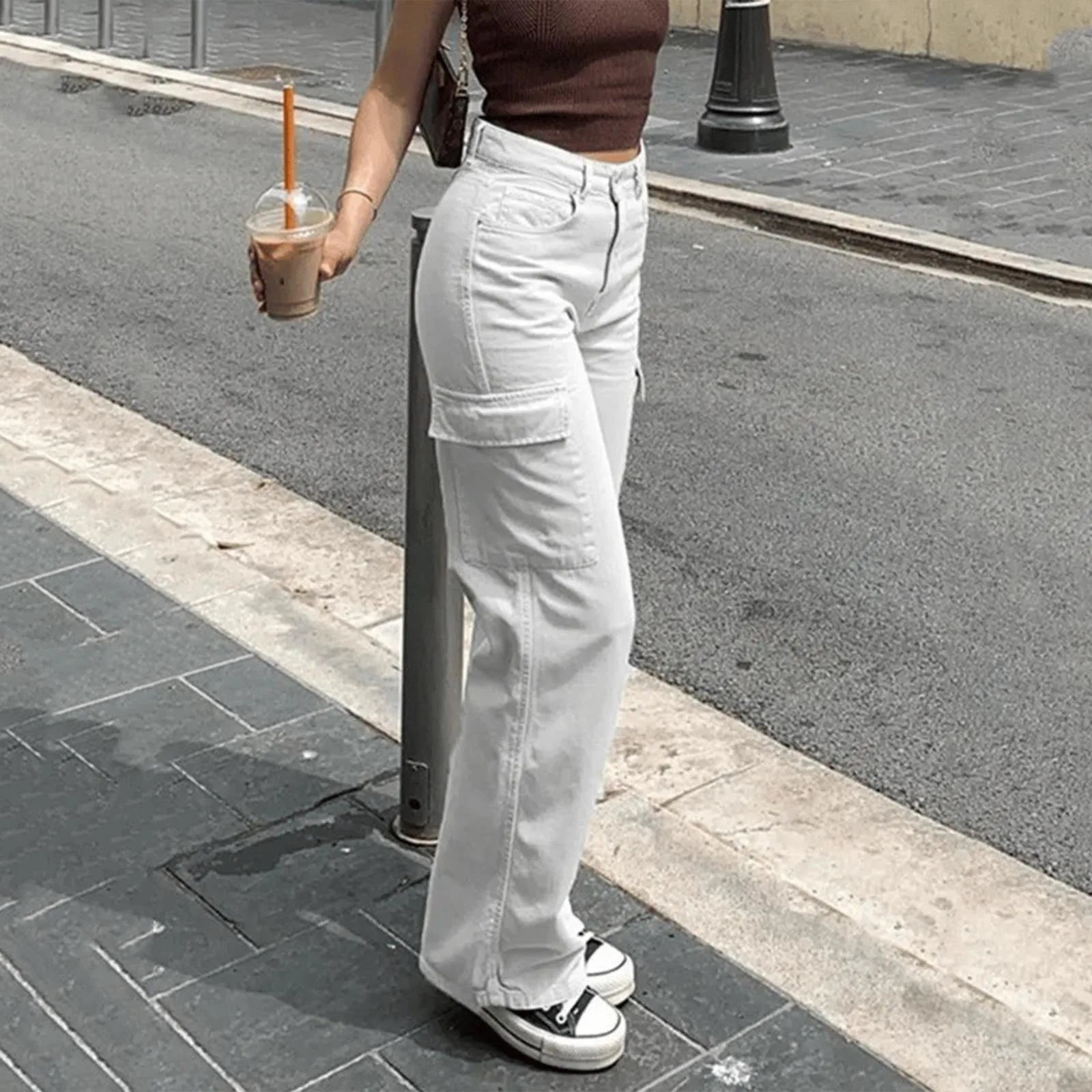 Person wearing light gray cargo pants and a brown top, standing on a sidewalk.