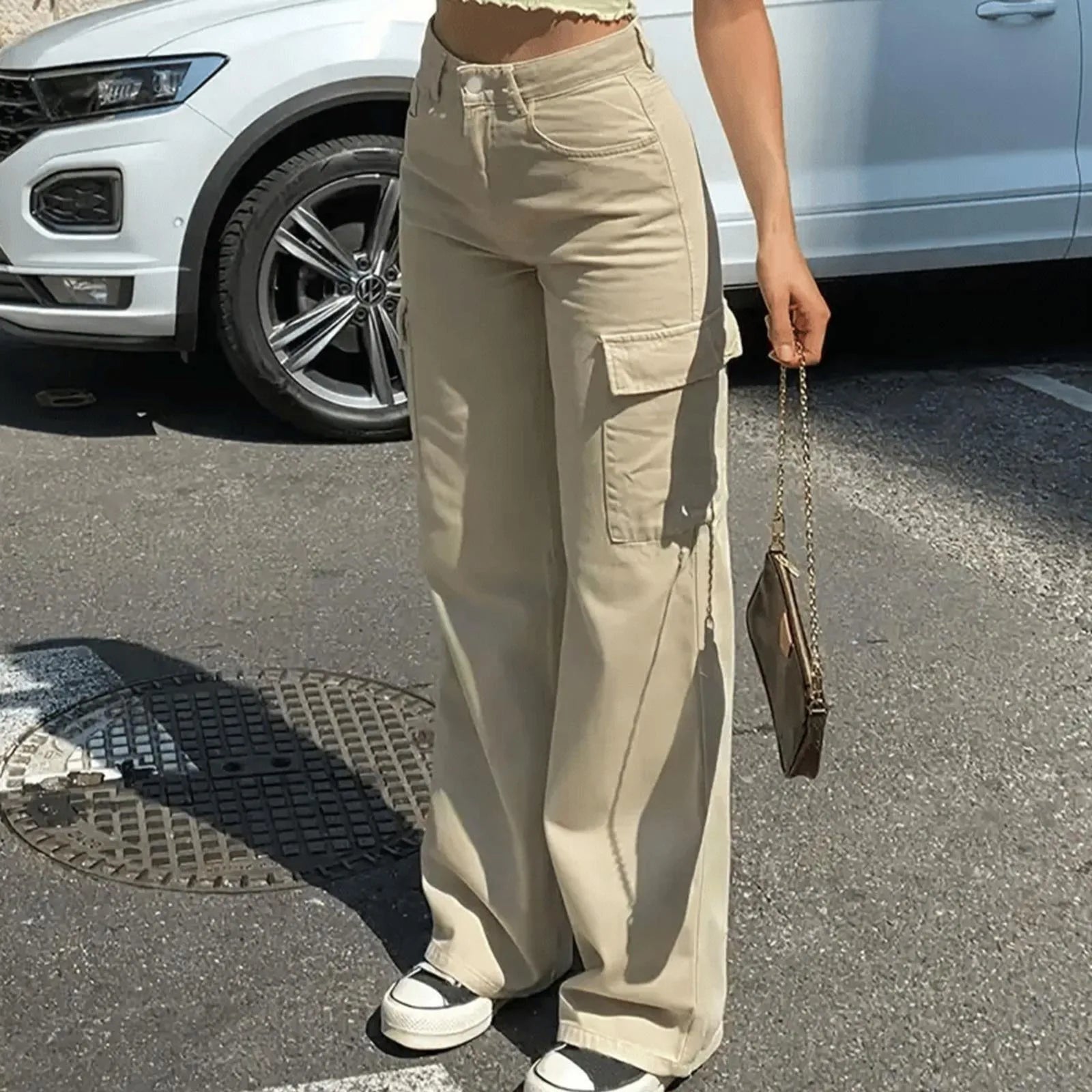 Person wearing beige cargo pants holding a small handbag on a street.
