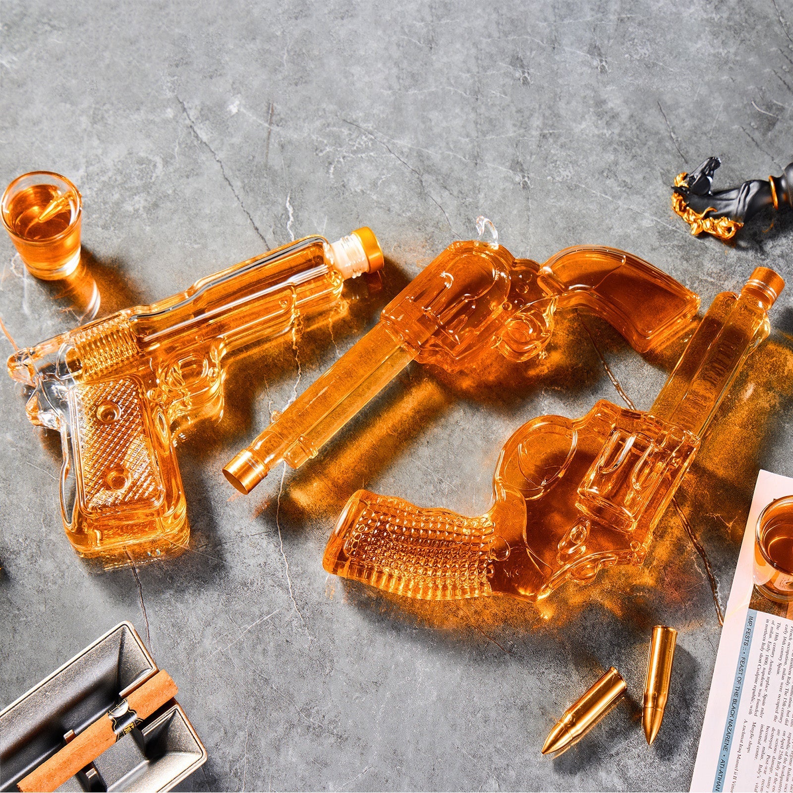 Transparent glass gun-shaped decanter with amber liquid on a gray surface.