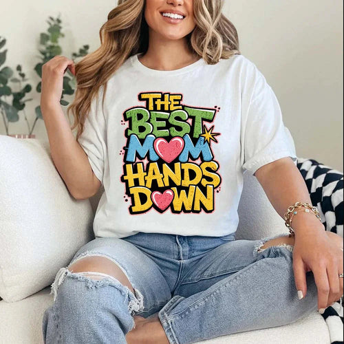 Person wearing a white t-shirt with colorful text design sitting on a couch.