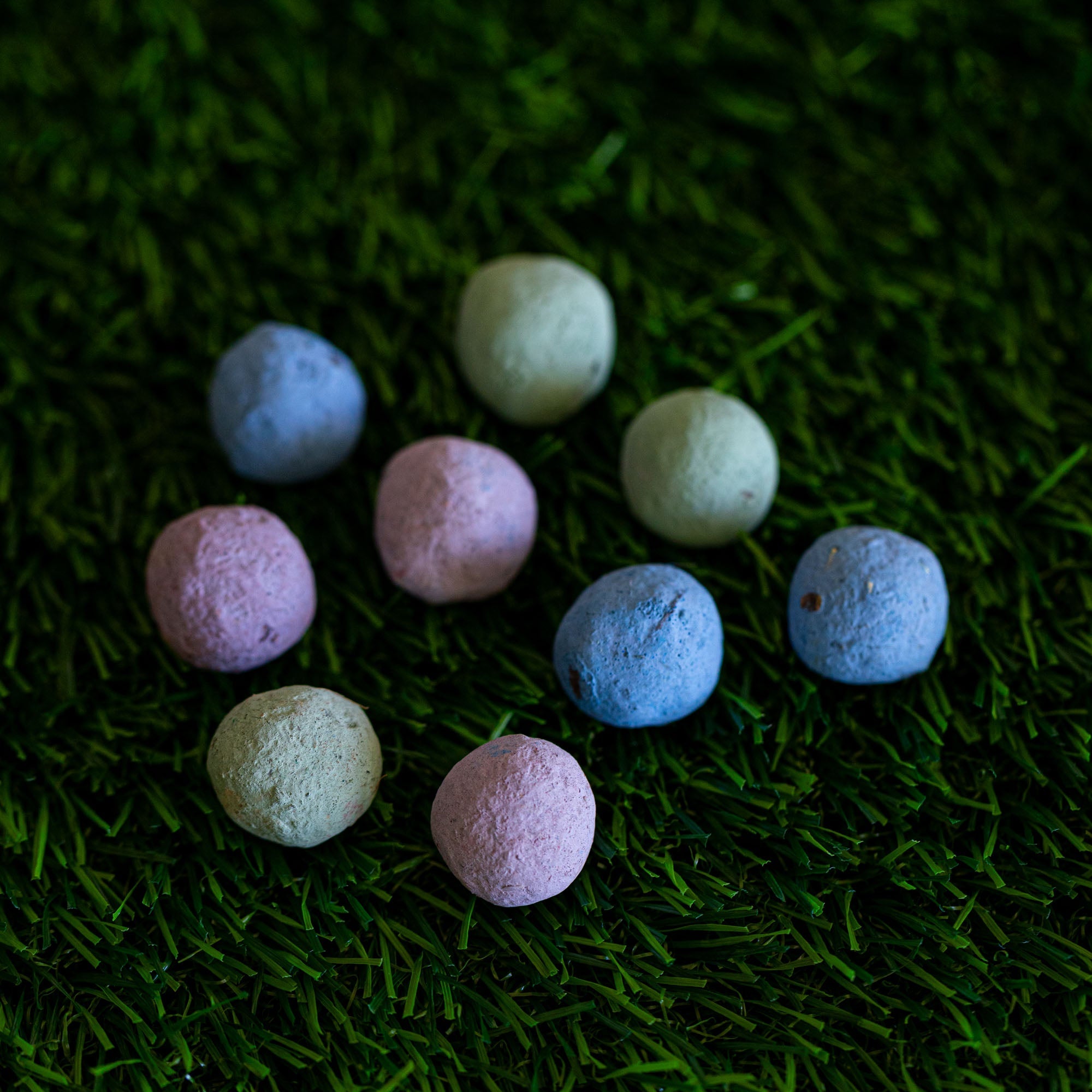 Pastel-colored seed balls on a green grass background