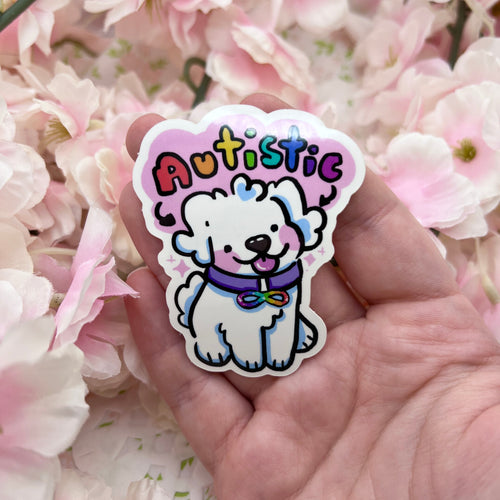 Sticker with a cartoon dog and 'Autistic' text held in front of pink flowers