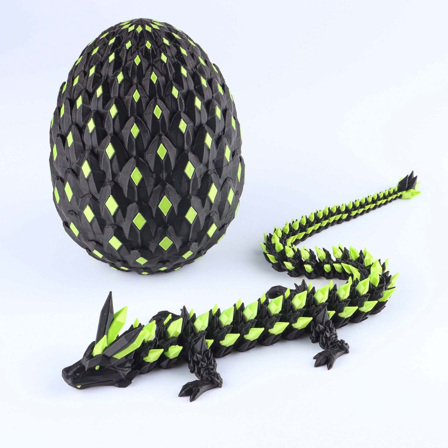 Black and green dragon toy with a matching egg on a white background