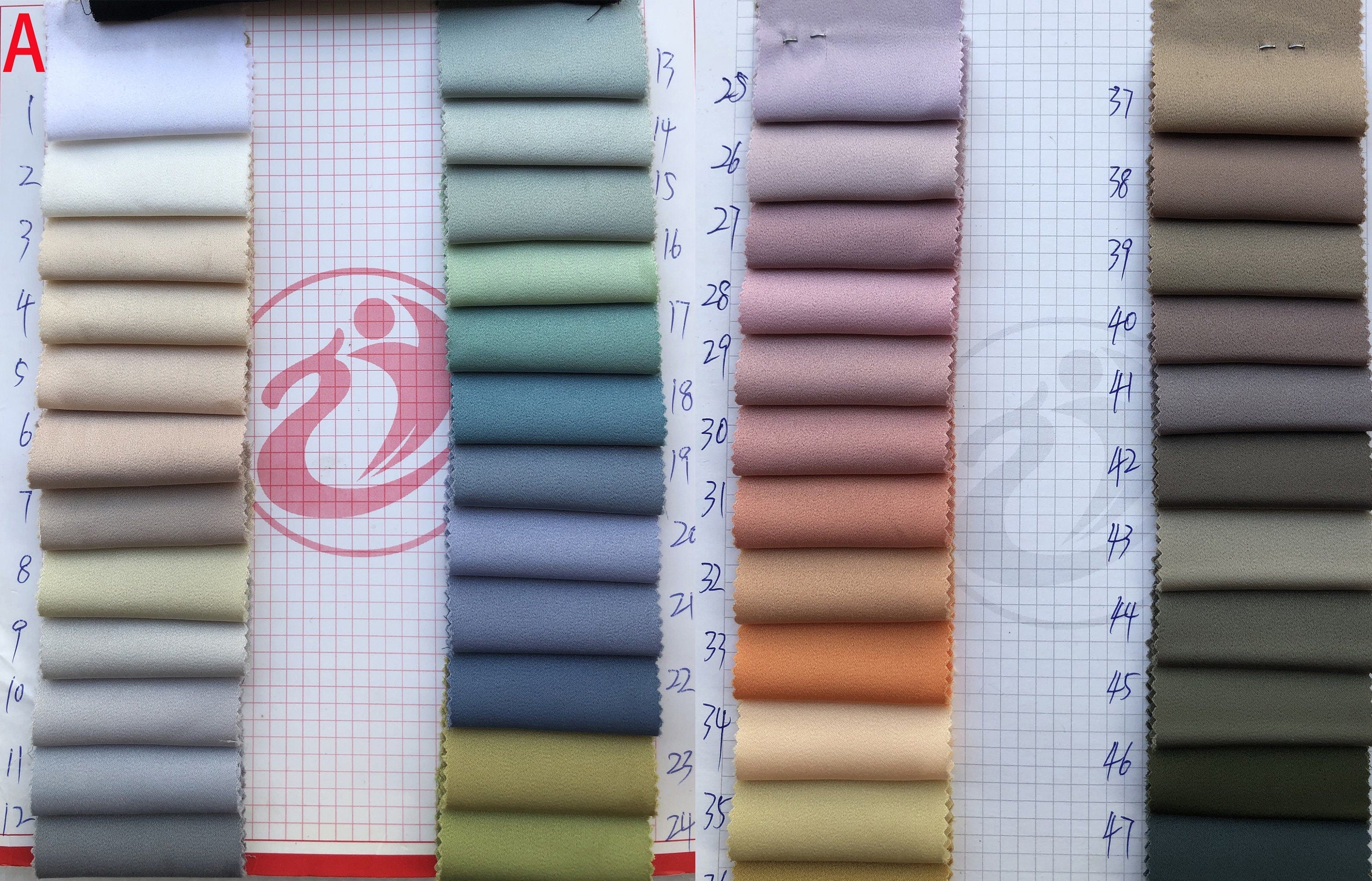 Fabric swatches arranged in a grid on a checkered background with a visible brand logo.