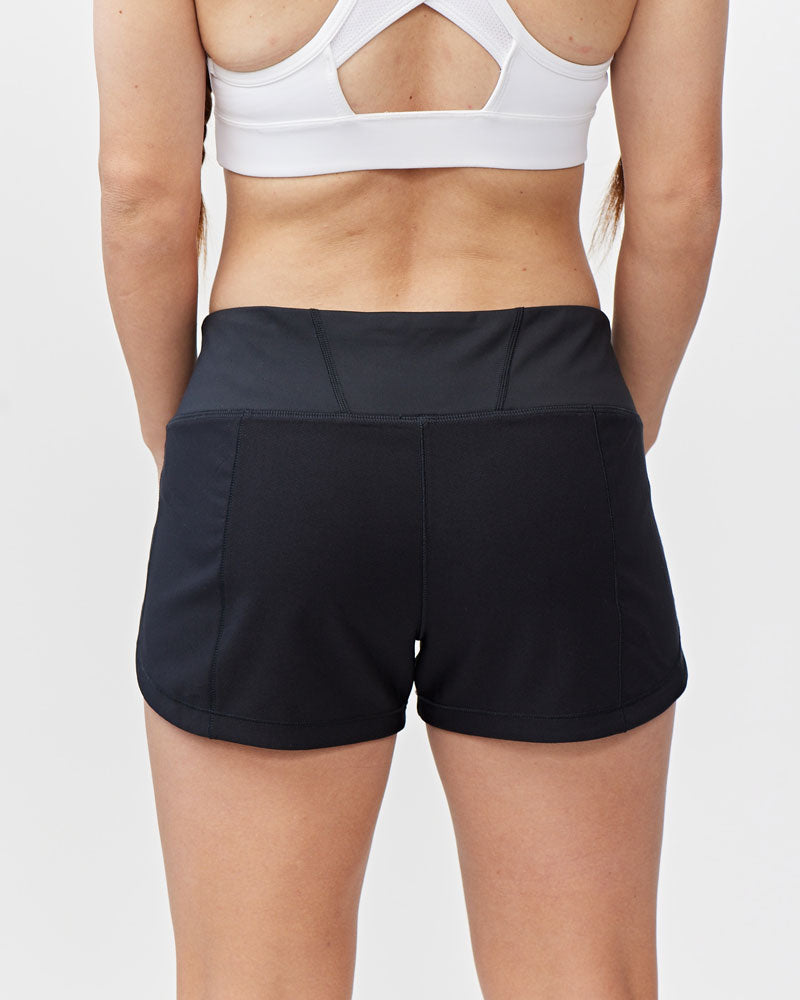 Person wearing black athletic shorts and a white sports bra on a light gray background