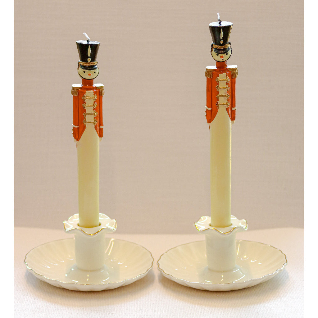 Two decorative candle holders with nutcracker design on a beige background