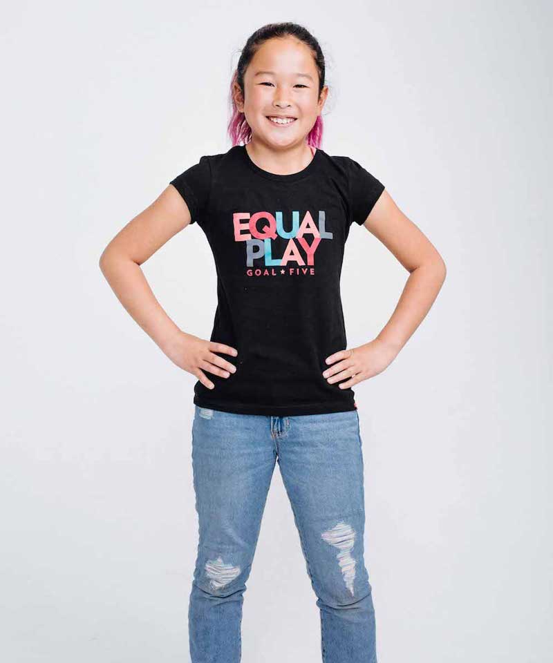 Young girl wearing a black t-shirt with 'Equal Play Goal Line' text on a white background