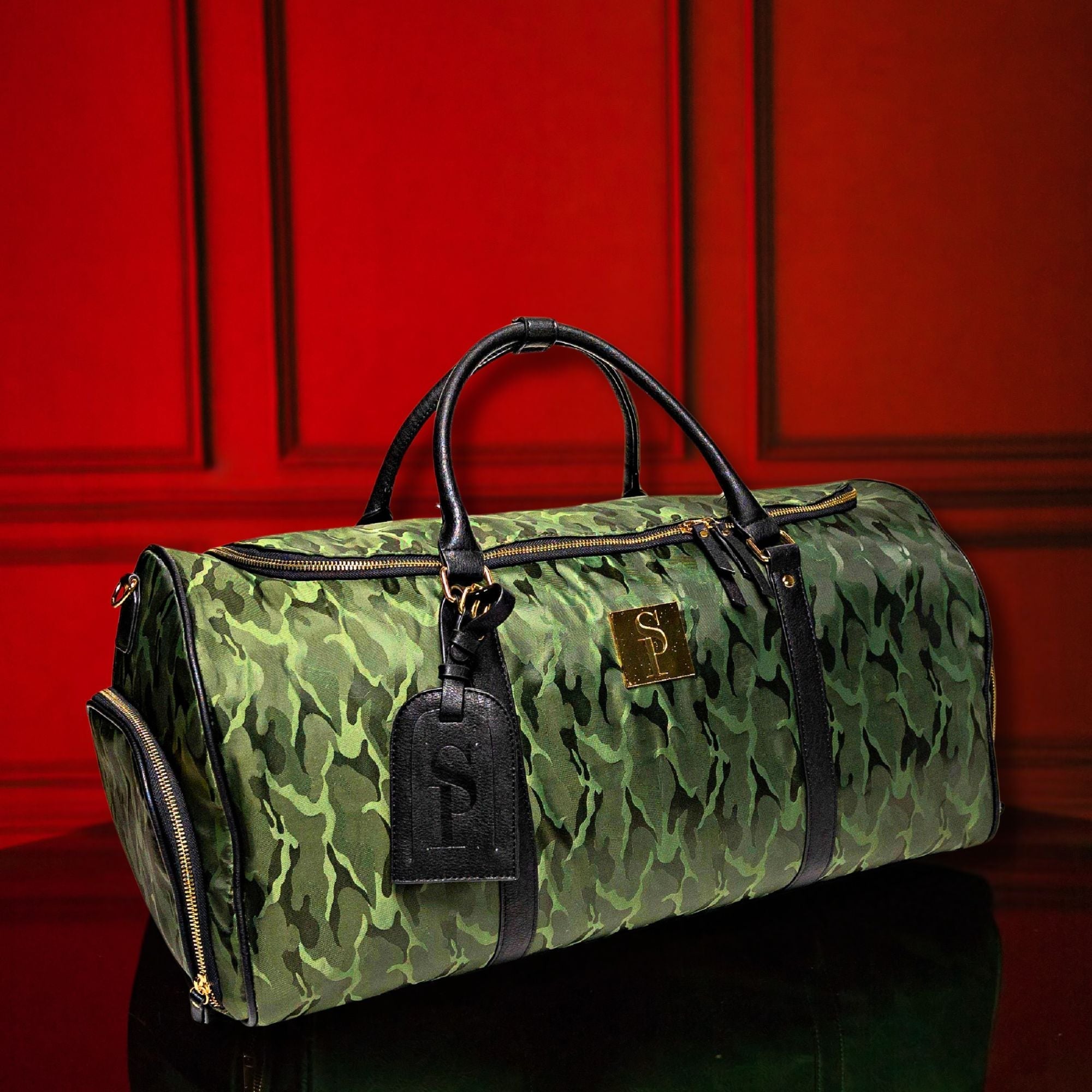 Green camouflage duffel bag with black accents against a red paneled wall