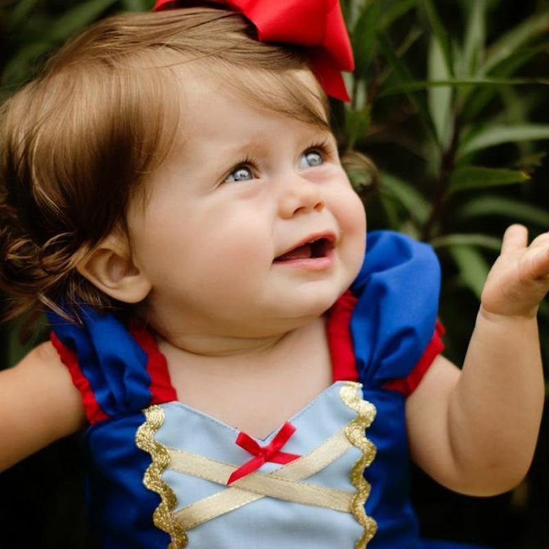 Child in Snow White costume with a red bow outdoors