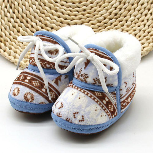 Pair of baby shoes with patterned design on a woven mat background
